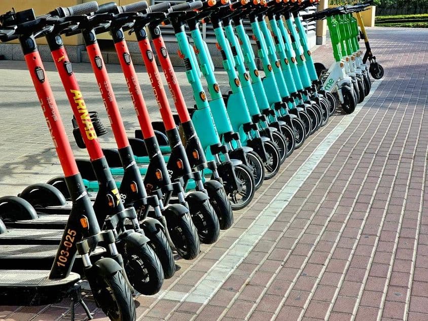 Rote, blaue und grüne Scooter warten in ihren Parkbereichen.