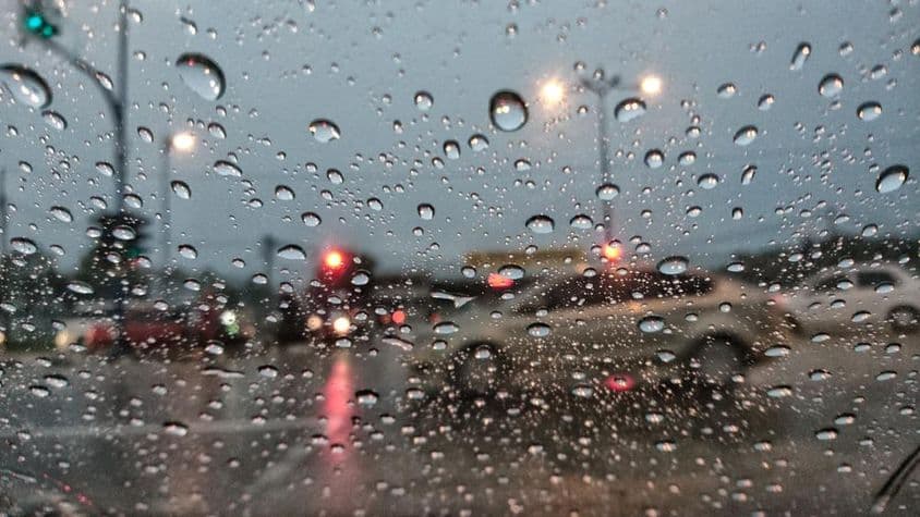 Autos erscheinen unscharf durch regennasses Glas.