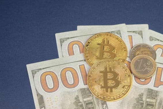US-Dollar über Bitcoin-Münzen neben 1-Euro-Münze