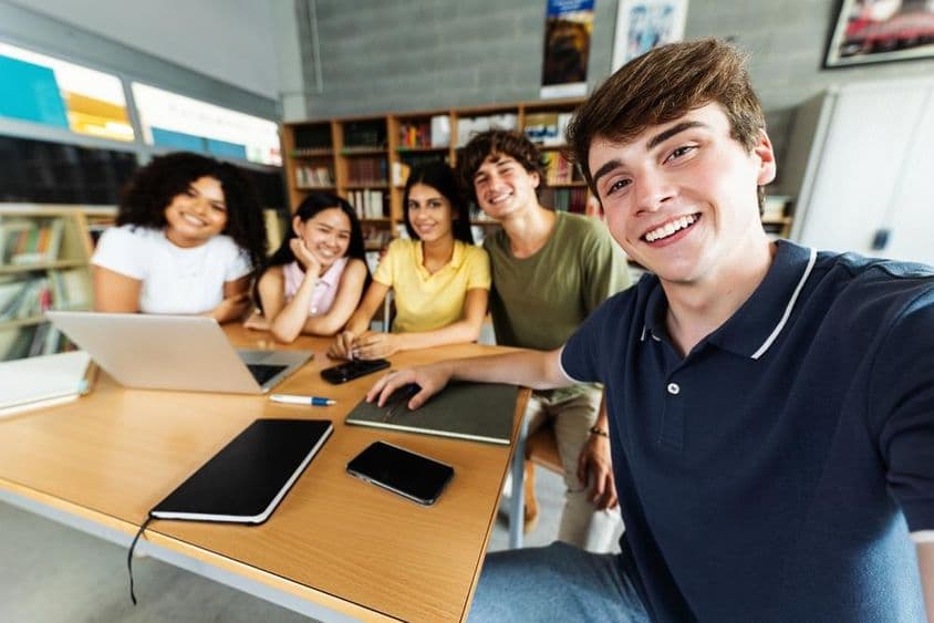 Studenten, die in der Bibliothek lernen, mit einem Notebook, Telefon und Notizblock auf dem Tisch.