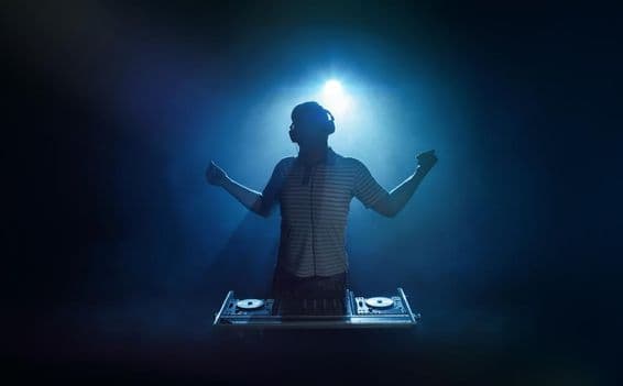 Eine Person steht hinter dem DJ-Pult.