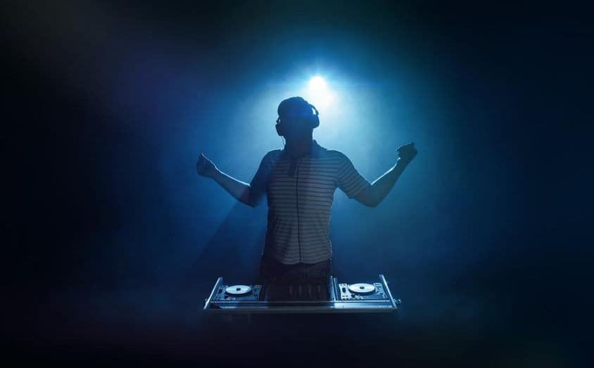 Eine Person steht hinter dem DJ-Pult.