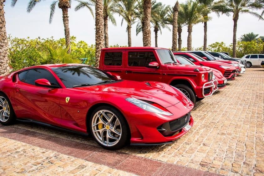 Rote Luxusautos in Dubai aufgereiht, einschließlich Ferrari, Porsche, Mercedes.