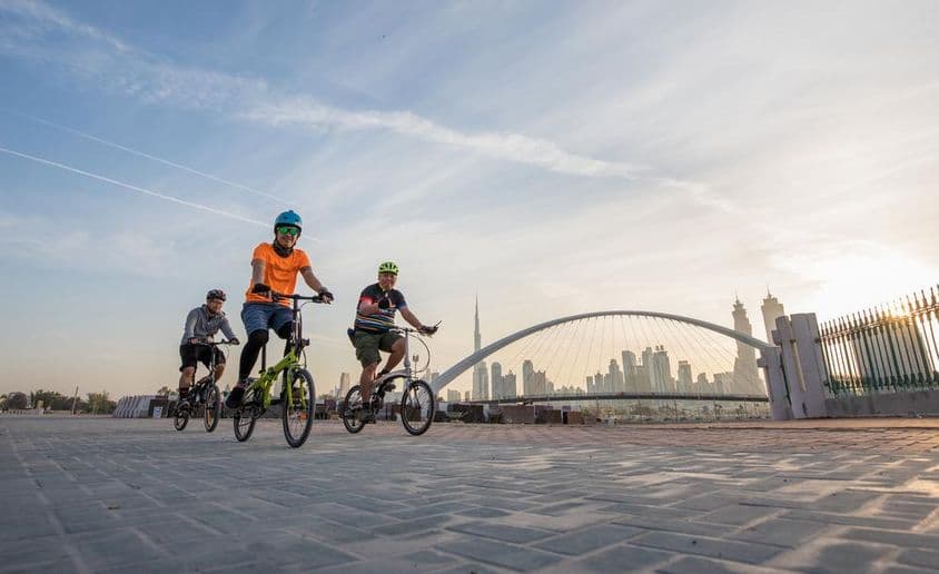 Radfahrer mit Helmen vor Burj Khalifa.