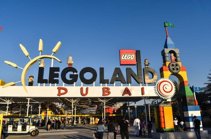 Eingang zu LEGOLAND Dubai mit Menschen und einem Golfwagen im Vordergrund.