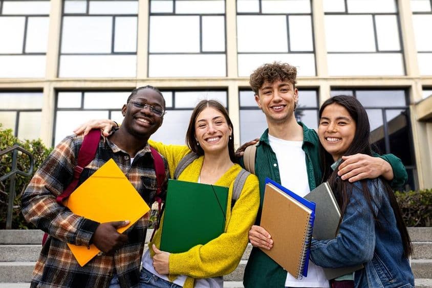 Studierende sind im Bild zu sehen, die Ordner halten.