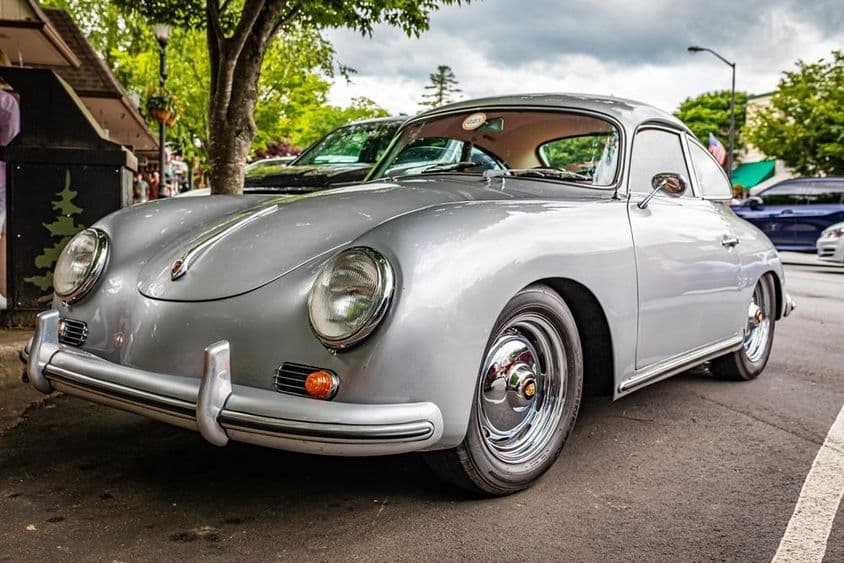 Ein Porsche 356A ist unter einem Baum geparkt zu sehen.
