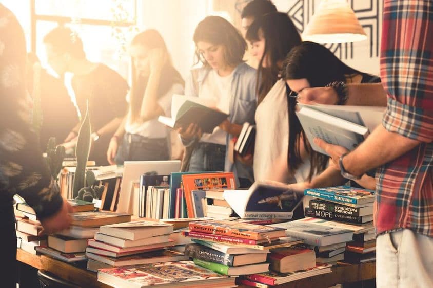 Studenten stöbern in Büchern auf einer großen Messe.