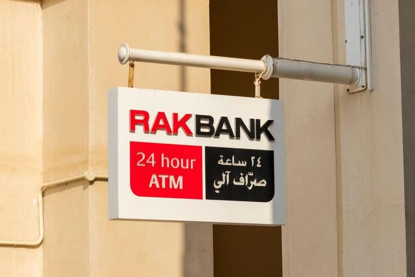 RAKBANK-Geldautomatenschild in rotem und teilweise schwarzem Text.