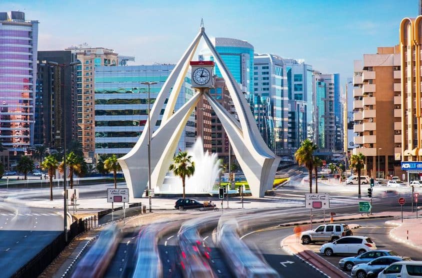 Erstaunlicher Uhrturm in Dubai mit Häusern im Hintergrund.