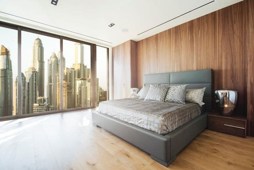 Innenraum eines Zimmers in Dubai mit Bett, Fensterblick auf Wolkenkratzer.