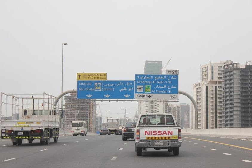 Al Khail Road Überkopfschild, mit einigen hohen Gebäuden im Hintergrund.