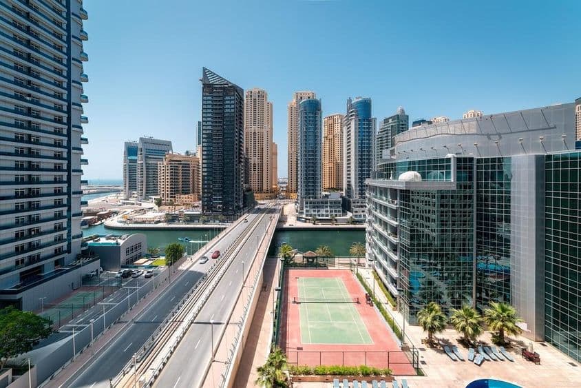 Ein Tennisplatz in Dubai mit Wolkenkratzern und einem Schnellboot auf dem Wasser.