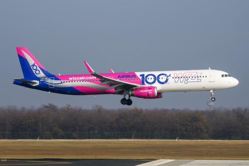Wizz Air Flugzeug fliegt in niedriger Höhe über die Landebahn.