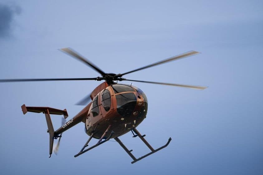 Ein leichter Hubschrauber fliegt in der Luft.