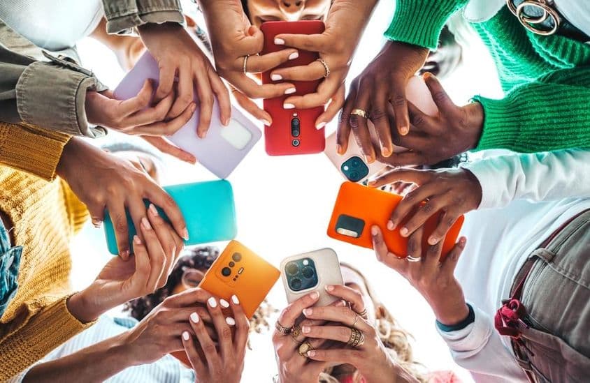 Menschen halten Telefone im Kreis, Hände von unten gesehen.