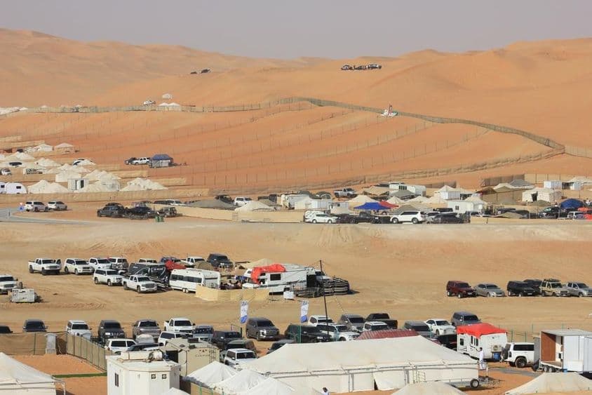 Liwa International Festival Szenerie in der Wüste mit Autos, Wohnmobilen und Zelten.