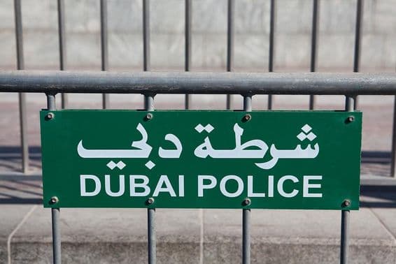 Dubai Polizeischild sichtbar auf einem Zaun.