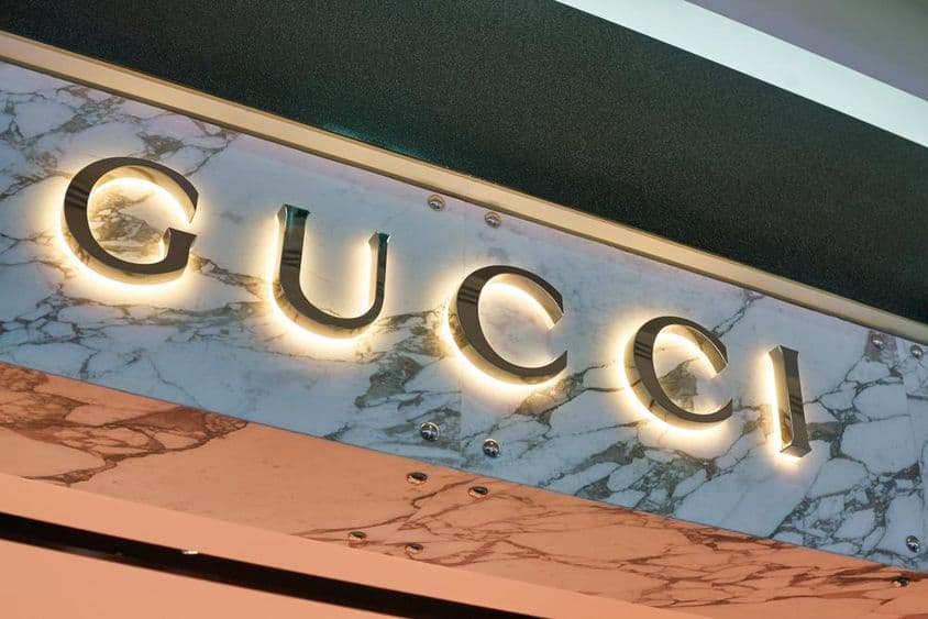 Gucci-Schriftzug in leuchtenden Buchstaben an einer Gebäudefassade.