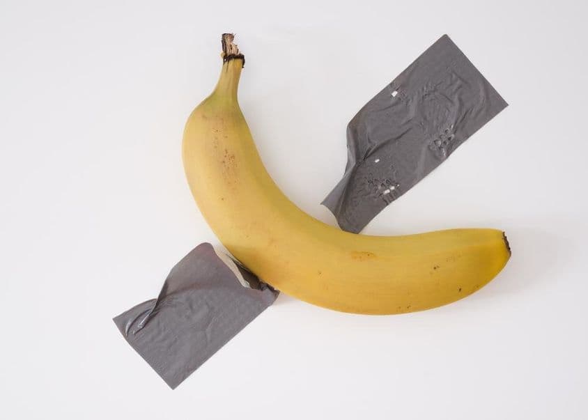 Eine Banane mit grauem Klebeband an die Wand geklebt.