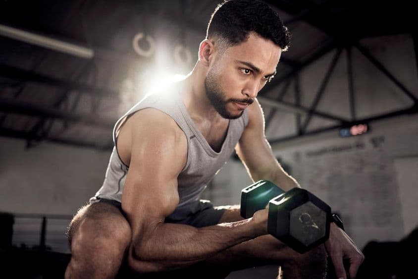 Ein muskulöser Mann stärkt seine Bizeps mit einem kleinen Hantel im Fitnessstudio.