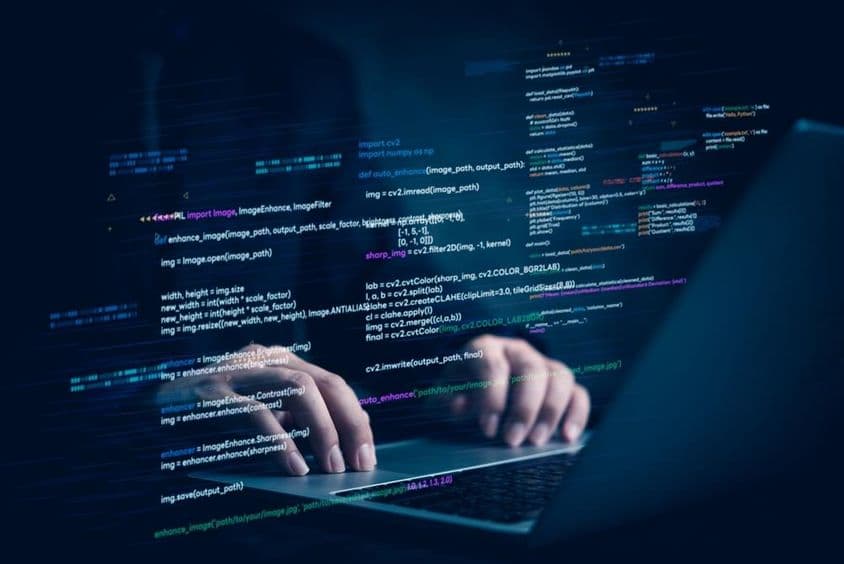 Ein Notebook mit zwei Händen, die an einem Computerprogramm arbeiten.