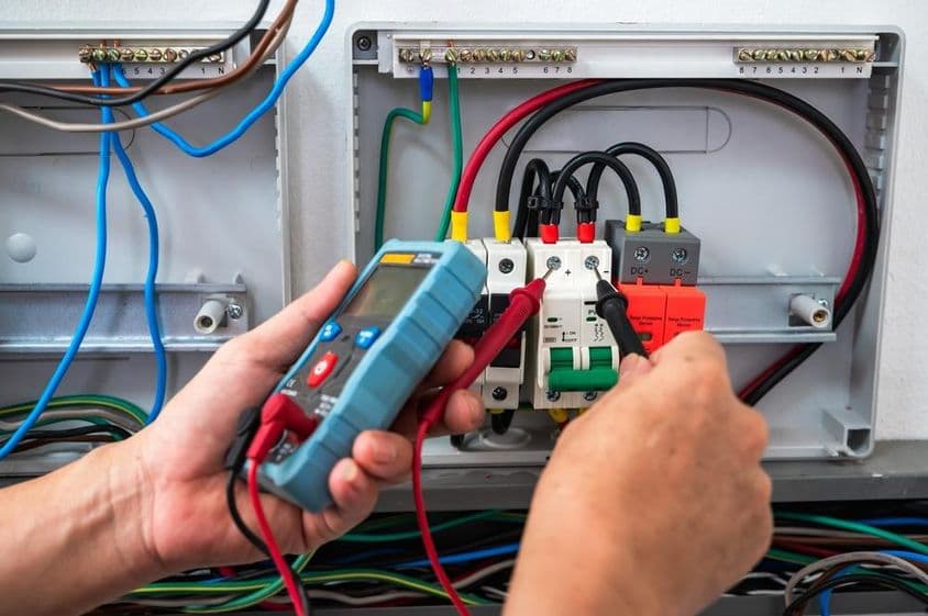 Elektriker überprüft eine Stromquelle mit einem Messgerät.