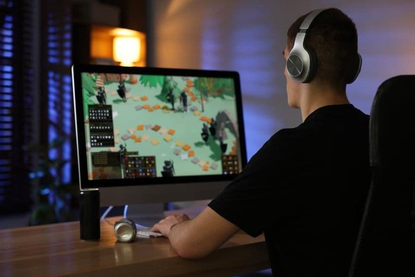 Ein älteres Kind spielt ein Videospiel an einem Computer an einem Schreibtisch.