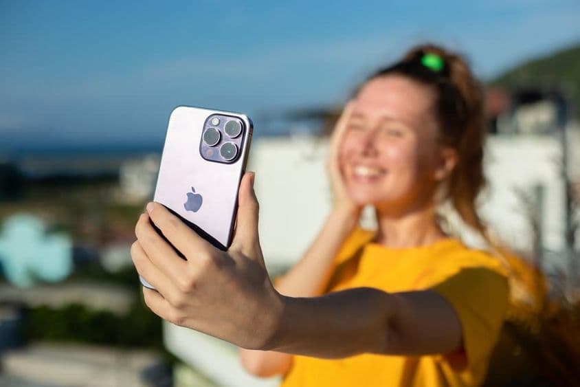 Junge Frau hält ein iPhone in der Hand.