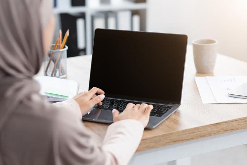 Muslimische Frau arbeitet an einem Laptop.