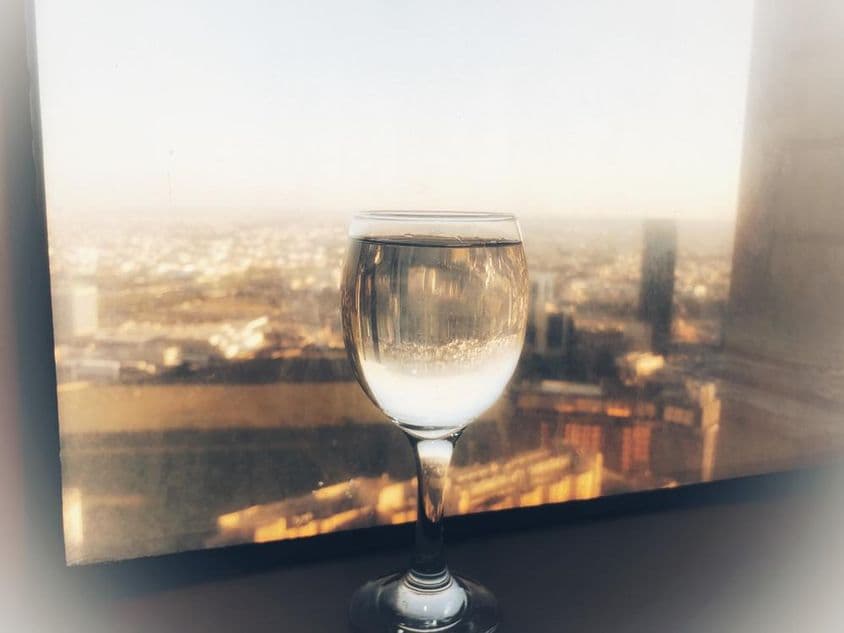 Ein Glas Wein am Fenster mit Stadtblick.