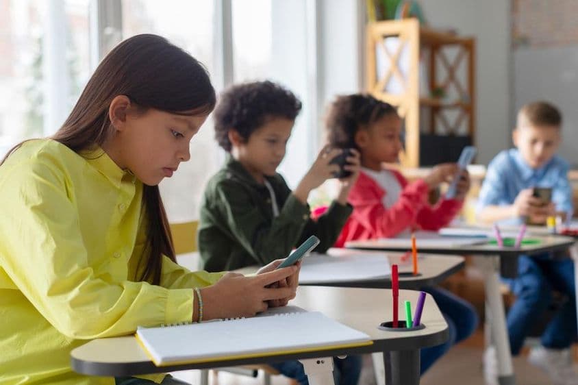 Kinder benutzen Telefone im Klassenzimmer.