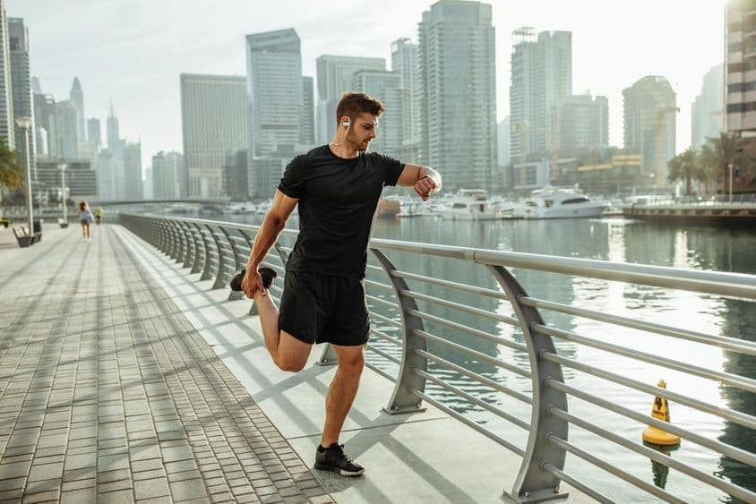 Junger Mann dehnt sich nach einem Lauf am Dubai-Kanal.