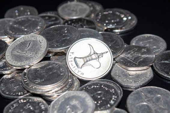 Eine Handvoll 1-Dhim-Münzen verstreut herum.
