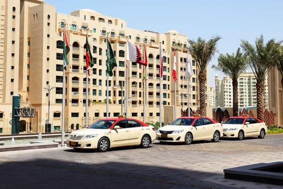 Dubai Taxis vor einem 10-stöckigen Wohngebäude.