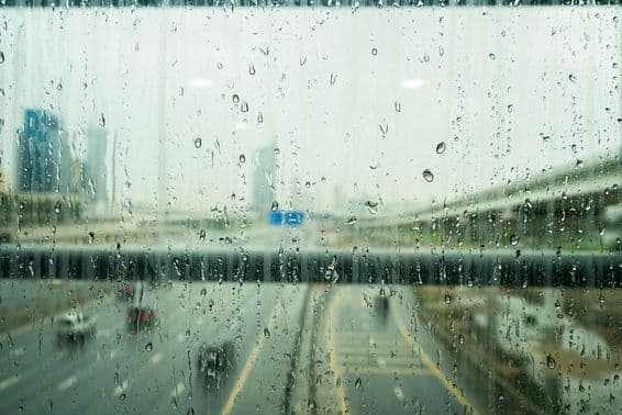 Regentropfen auf einem Fenster mit ein paar verschwommenen Wolkenkratzern im Hintergrund.