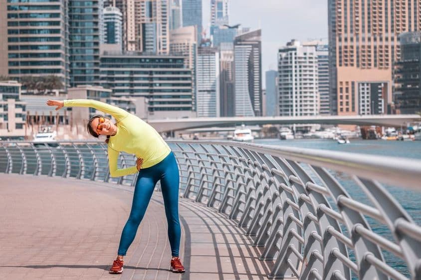 Dubai junges Mädchen, das sich nach einem Lauf an der Marina dehnt.