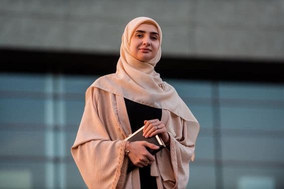 Dubai Universität Studentin, die ein Buch hält.