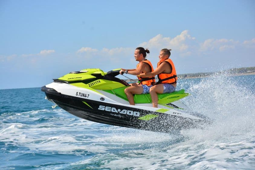 Junges Paar sitzt auf einem Jetski.
