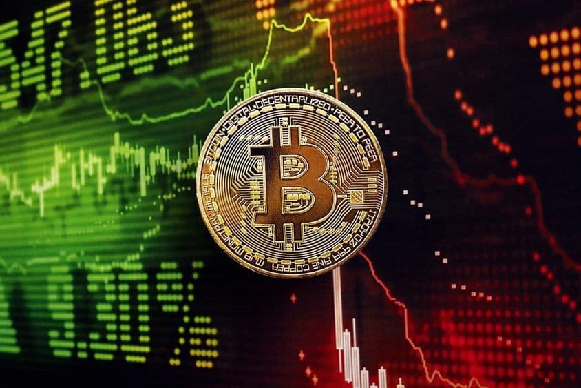 Bitcoin-Münze mit einem Börsenchart im Hintergrund.