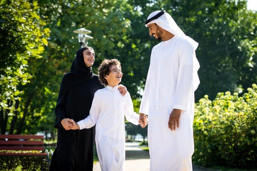 Muslimische Familie geht in einem Park in Dubai spazieren.