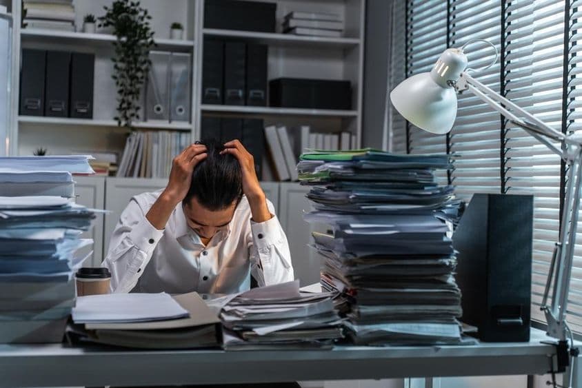 Büroangestellter hält Kopf wegen überwältigender Arbeit.