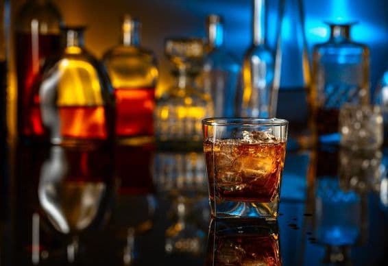 Whisky mit Eis auf einem schwarzen Tisch in einer Bar.