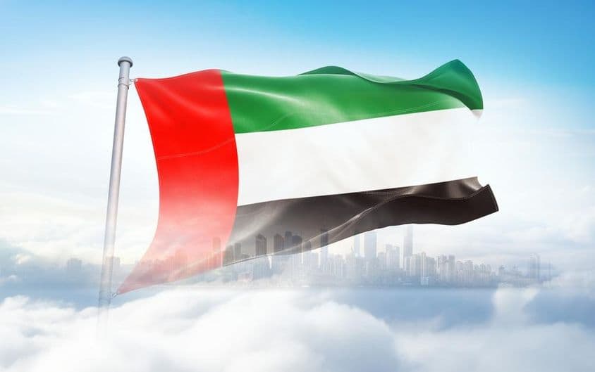 VAE-Flagge weht in den Wolken, Wolkenkratzer im Hintergrund.
