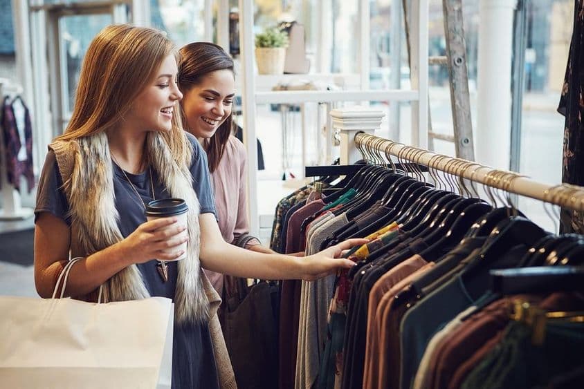 Frauen lachen und trinken Kaffee in einer Boutique.