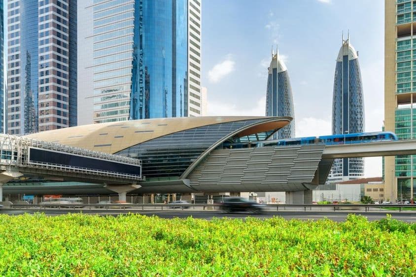 Eine Dubai Metro erreicht die Financial Centre Station im Zentrum von Dubai, VAE, mit beeindruckenden Wolkenkratzern im Hintergrund.