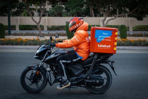 Motorradfahrer liefert Essen, navigiert geschäftige Straßen in Dubai.