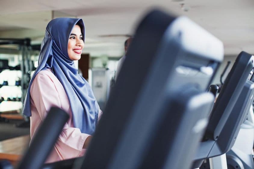 Muslimische Frau trainiert im Fitnessstudio und trägt einen Hijab.