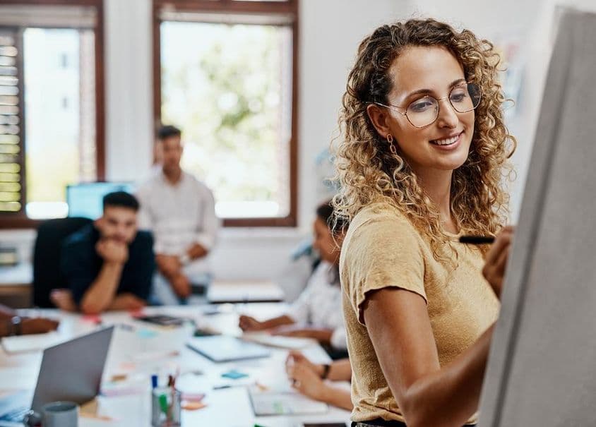 Coaching-Meeting und Präsentation mit einer Designerin an einem kreativen Arbeitsplatz zur Kompetenzentwicklung.