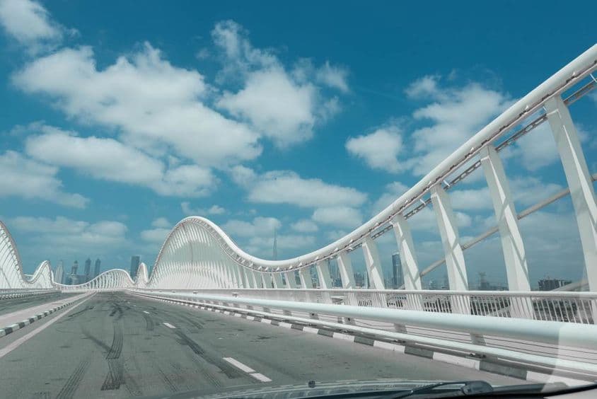 Weiße moderne abstrakte Brücke mit blauem Himmel und Wolken im Hintergrund.